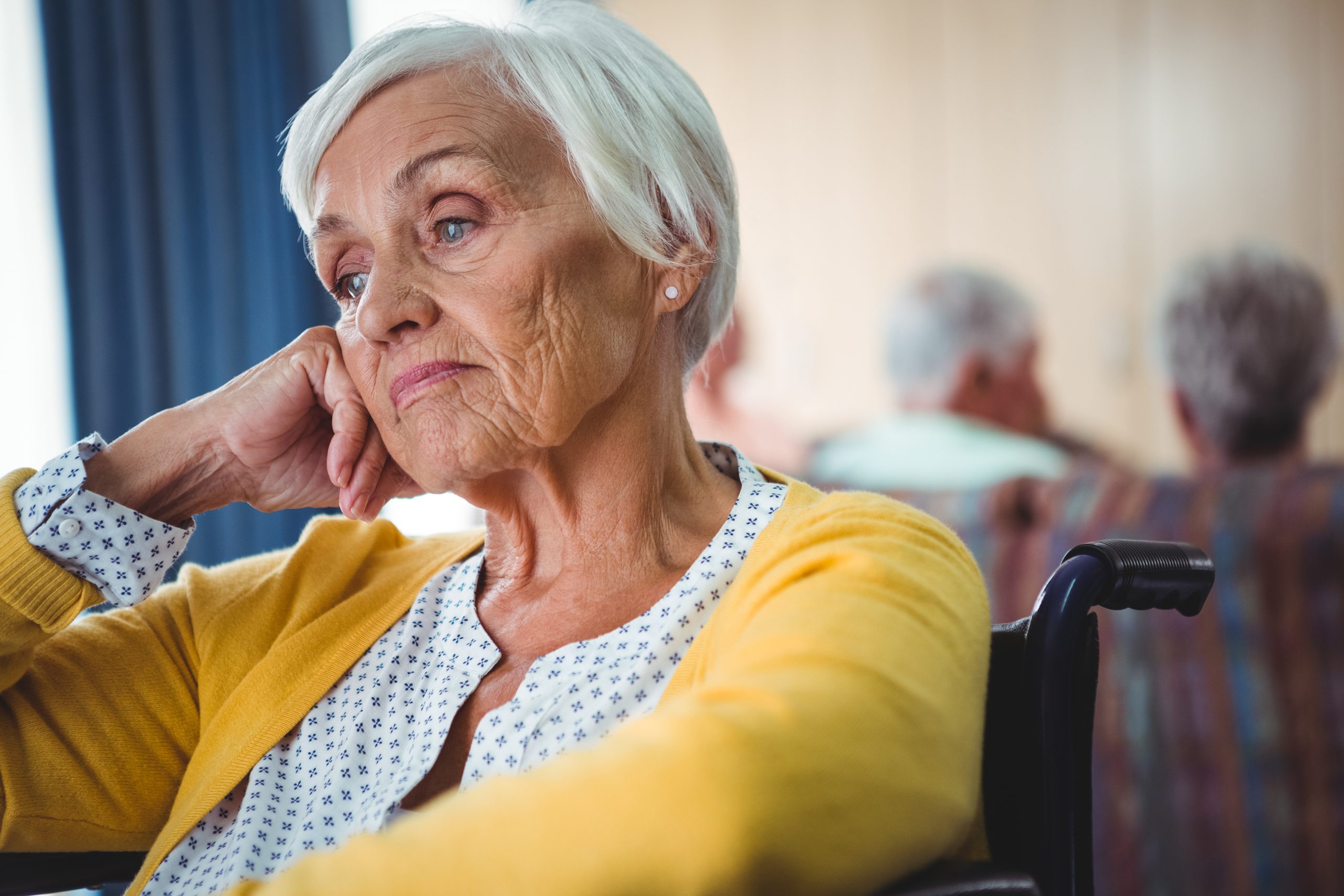 Senior woman in wheelchair look worried with hand holding her head